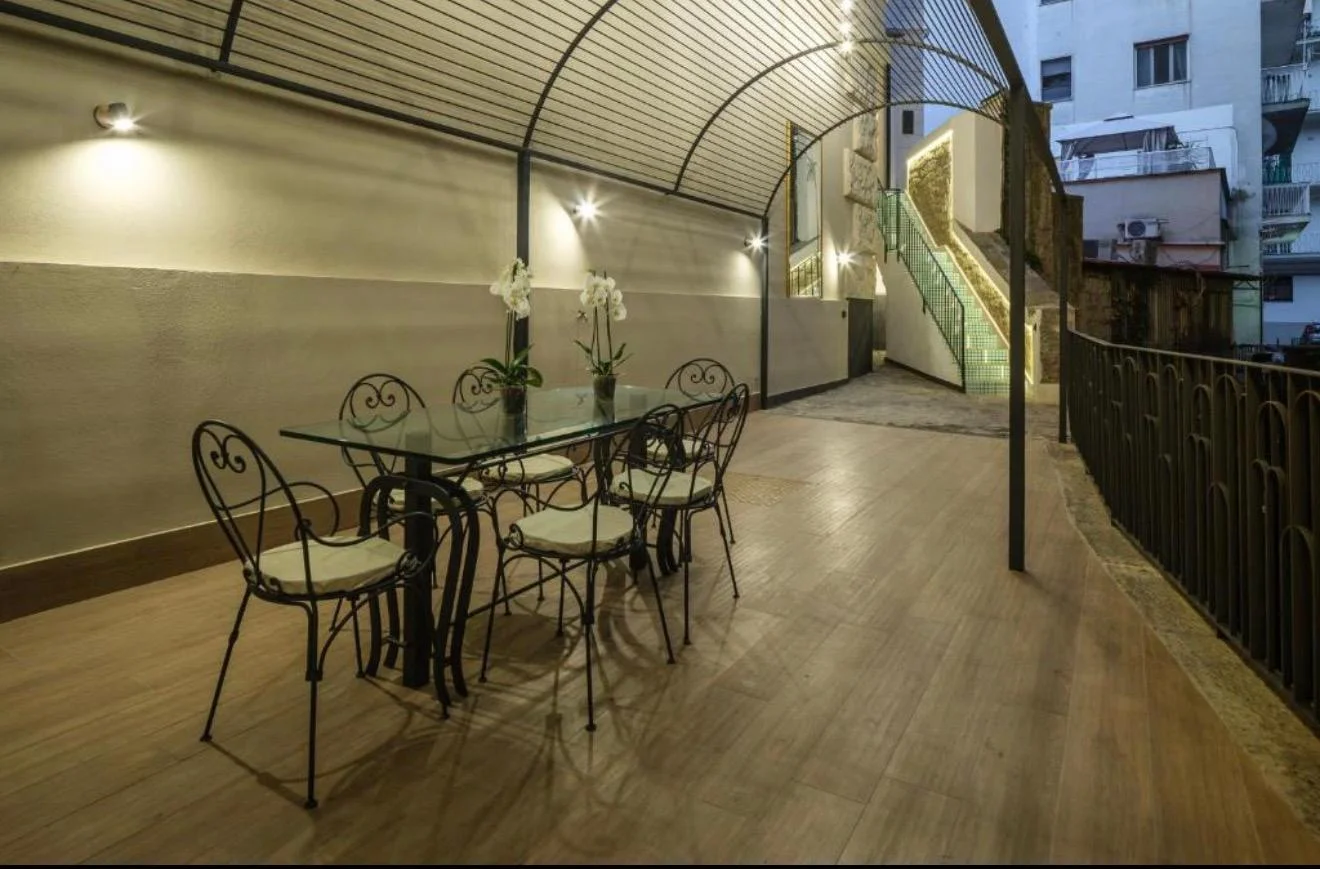 Terrazzo illuminato di sera con tavolo in ferro battuto